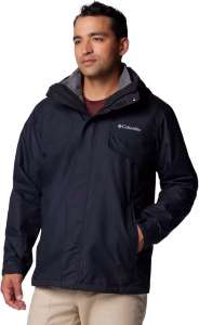 Male model wearing Columbia Men’s Bugaboo III Interchange Jacket in black, paired with beige pants and black shoes.